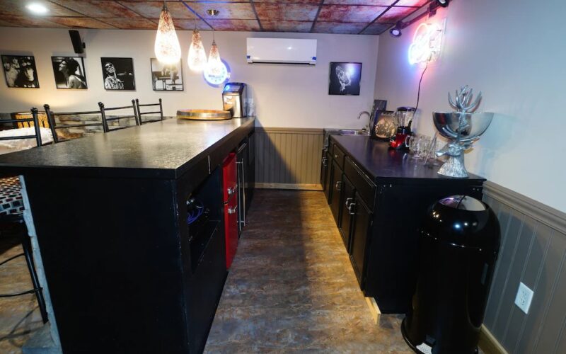 Bar has a wine refrigerator, a microwave, a small refrigerator/freezer, ice maker and glassware